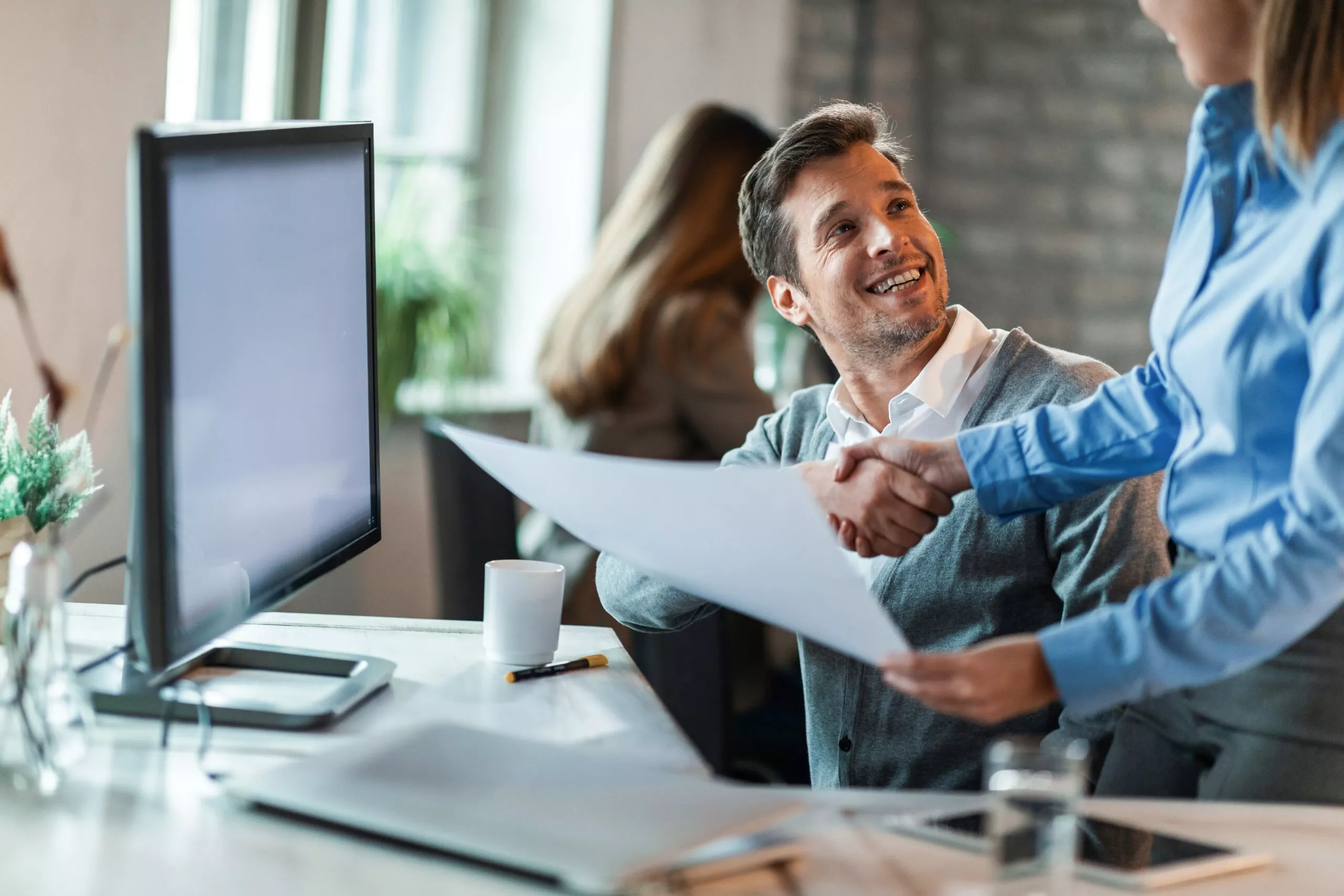 Happy businessman shaking hands with female colleague and congratulating her on excellent job she did.
