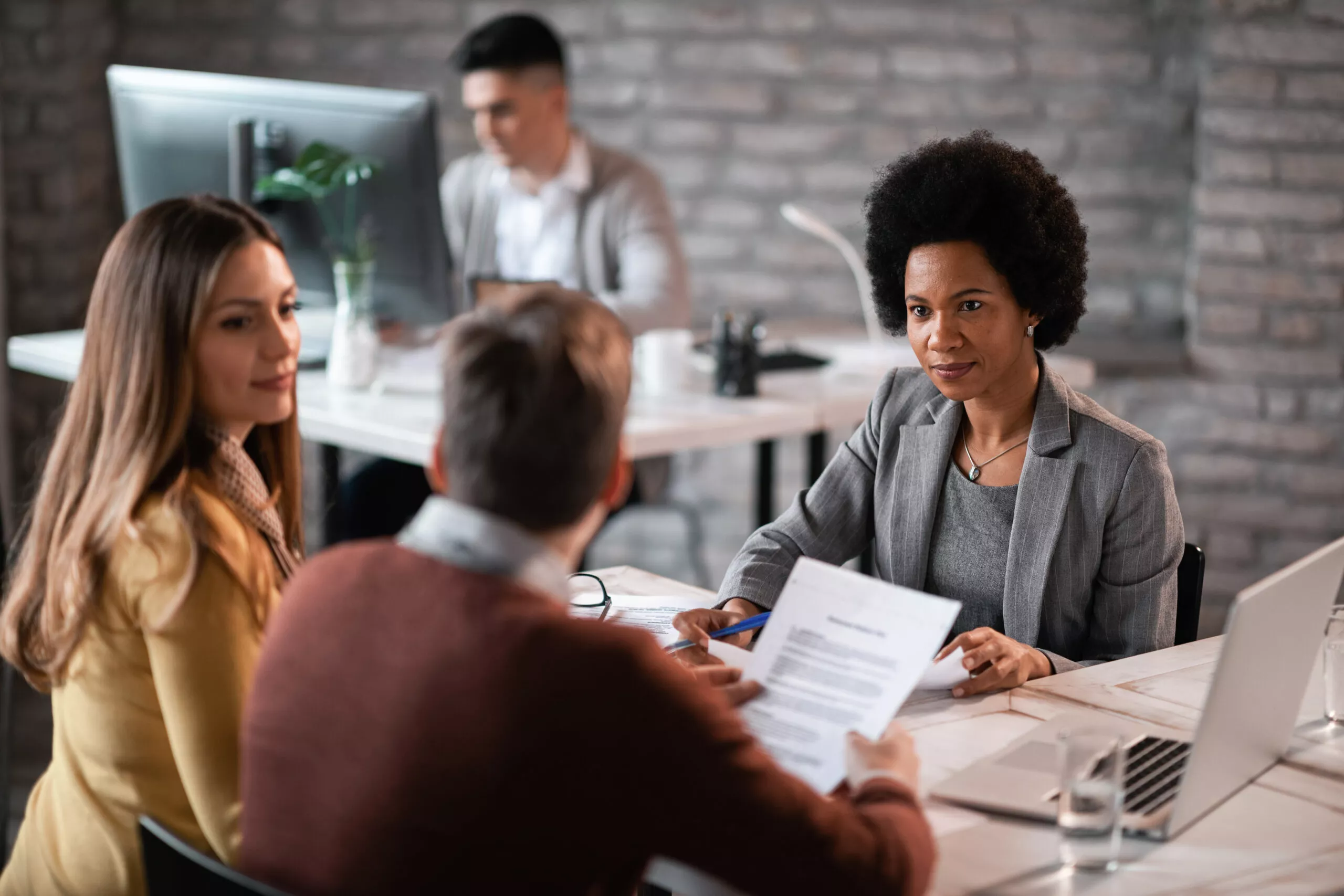 African American financial advisor going through paperwork with her clients while having a meeting in the office.